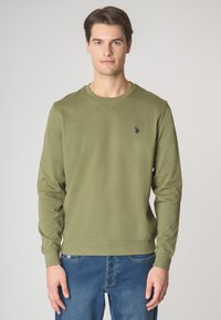 Felpa verde oliva a girocollo con maniche lunghe, tessuto texturizzato, polsi e orlo a costina, con un piccolo logo blu navy sul petto.