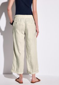 Ljusgröna linbyxor med elastisk midja, vida ben, upprullade ärmmuddar och två bakfickor.