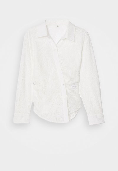 Chemise blanche à boutons avec un tissu en dentelle à motifs cachemire, manches longues, col et ourlet légèrement courbé.