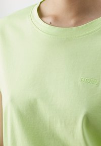 Zielona bawełniana koszulka z okrągłym dekoltem, krótkimi rękawami i subtelnym haftowanym logo "BOSS" na piersi. Miękka tekstura.