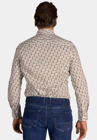 Een button-up shirt met een witte achtergrond, gekenmerkt door een meerkleurig cirkelpatroon. Lange mouwen, standaard kraag en een gladde stoftextuur.