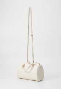 Sac à main en cuir blanc à textures granuleuses avec deux anses supérieures et une bandoulière amovible. Doté de quincaillerie en ton doré et d'une forme arrondie.