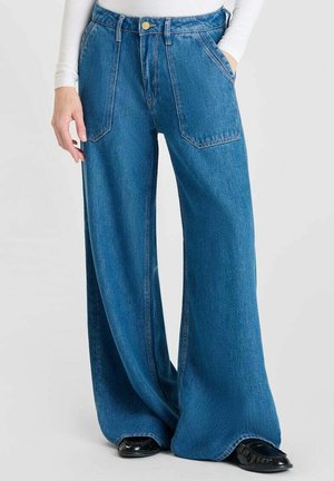 Jeans en denim bleu à jambes larges avec une taille haute, deux poches avant et une fermeture par bouton. Le tissu a une finition lisse et texturée.