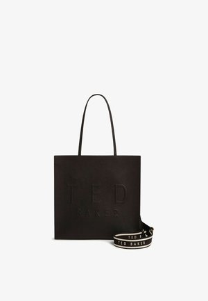 Sac cabas carré noir avec de fines anses et un logo "TED BAKER" embossé, accompagné d'une bandoulière noire et blanche amovible.