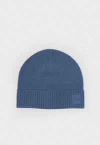 Căciulă tricotată albastră cu manșetă ribbed, având o etichetă logo pătrată. Textură moale de lână, vârf rotunjit și o finisare netedă.