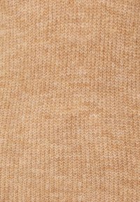 Tessuto a maglia di colore beige chiaro, caratterizzato da una consistenza morbida con un sottile motivo di fini fili intrecciati. Ideale per indumenti.