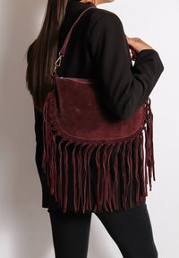 Borsa a spalla in suede bordeaux con lunghi frange, forma arrotondata, laccatura decorativa e hardware a contrasto per la tracolla.