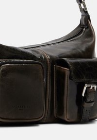 Brązowa skórzana torba na ramię o gładkiej fakturze, wyposażona w kieszeń na zamek błyskawiczny i zapięcie na klamrę, prezentująca zakrzywiony kształt.