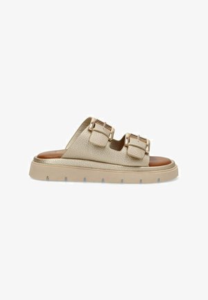 Sandalias de deslizamiento beige con dos correas ajustables, material superior texturizado y una suela gruesa de color claro. Detalle del reposapiés marrón visible.
