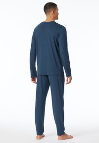 Herren-Pyjama-Set in Marineblau mit langen Ärmeln, aus weichem Stoff hergestellt; verfügt über ein einfaches Design, geraden Schnitt und elastischen Bund an der Hose.