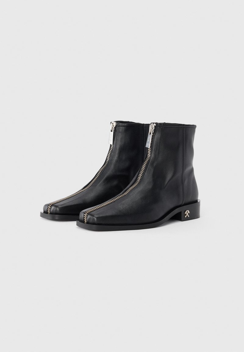 Bottines en cuir noir avec des zips �à l'avant, à bouts carrés, au design minimaliste et à talon bloc bas avec un petit détail d'accent.