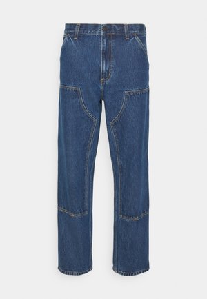Jean en denim bleu avec une coupe droite, poches avant à patch et coutures contrastées. Le tissu a une texture et une finition classiques.