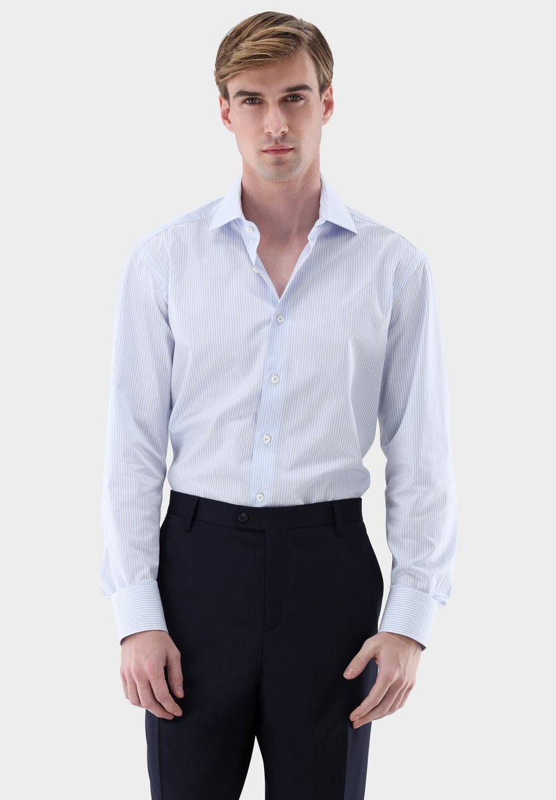 Hellblau-weiß gestreiftes Hemd mit Kragen, langen Ärmeln und durchgehender Knopfleiste. Kombiniert mit dunkelblauen Hosen. Glatte Textur.
