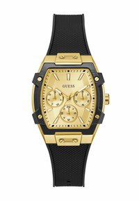 Orologio dorato con quadrante quadrato, cinturino in gomma nera, tre sotto-quadranti e dettagli testurizzati attorno alla cassa. Presenta il logo del marchio.