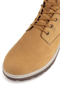 Hnedé semišové členkové čižmy s okrúhlym špičkou, kontrastnou gumovou podrážkou, šnurovaním a spevneným šitím pozdĺž okrajov.