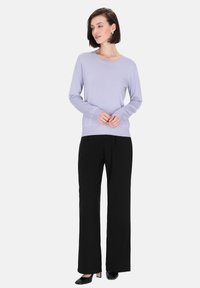 Maglione lungo a maniche concollo rotondo in lavanda chiara, abbinato a pantaloni a gamba larga neri e scarpe con tacco nere. Tessuto morbido, design semplice.
