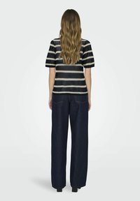 Top rayé tricoté en marine et crème, à manches courtes, associé à un jean large taille haute bleu foncé, offrant une coupe décontractée et des jambes droites.