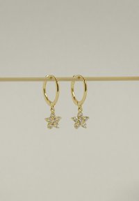 Pendientes de aro de oro con un charm de estrella colgante, adornados con detalles brillantes, con un acabado suave y un diseño minimalista.