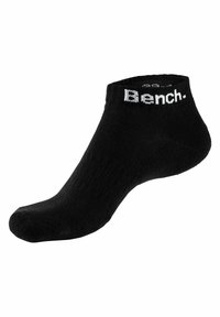 Calcetín negro hasta el tobillo hecho de tela suave. Presenta un puño acanalado con el logotipo "Bench." en blanco. Textura suave con una forma ajustada.