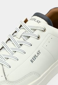 Weißer Replay-Sneaker mit schwarz genähten Schnürsenkeln, schwarzem Replay-Logo an der Seite und auf der Zunge sowie dunklem, gepolstertem Kragen.