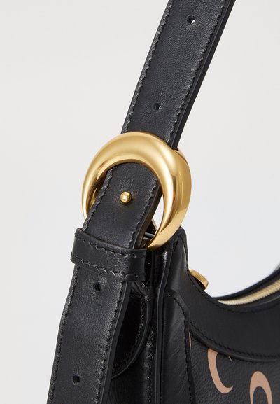 Correa de bolso de cuero negro con un anillo de herrajes en tono dorado. Superficie texturizada, costura detallada y acabado suave.