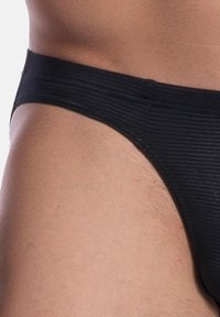 Schwarze Badebrieft mit gerippter Textur für Männer, ausgestattet mit einem breiten Bund und minimaler Bedeckung. Der Stoff ist glatt und passgenau.