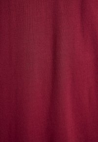 Red cotton fabric with a smooth texture, featuring a subtle ribbed pattern. The surface appears even and consistent throughout.