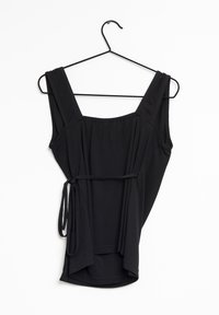 Haut sans manches noir en tissu léger, avec de larges bretelles, une taille cintrée avec un lien et une silhouette drapée.