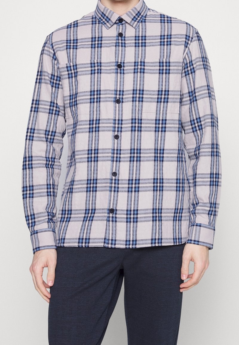 Napapaita napakaduvi sinisestä ja harmaasta ruudullisesta kuviosta, joka on valmistettu kevyesti teksturoidusta kankaasta. Paidassa on klassinen kaulus ja pitkät hihat.