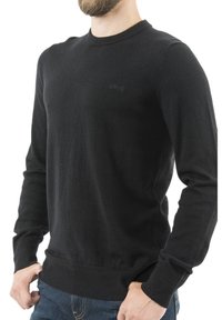 Czarny sweter z długim rękawem wykonany z dzianiny, z okrągłym dekoltem i ściągaczami przy rękawach. Posiada małe logo na piersi.