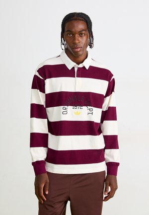 Langærmet rugbytrøje i bordeaux og hvide striber. Har en polo-krave, knaplukning og broderet logo-detail på brystet.