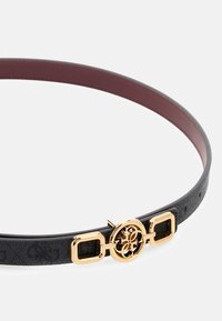 Ceinture noire texturée avec un intérieur bordeaux lisse, ornée d'une boucle circulaire dorée et d'accents rectangulaires.