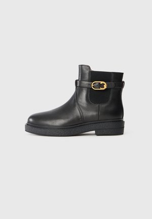 Black leather ankle boots with a rounded toe, elastic side panel, and gold buckle detail. Textured black rubber sole for grip.