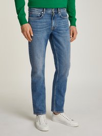 Blue denim jeans with a straight-leg fit, featuring classic five-pocket design and subtle whiskering. Paired with white sneakers and a green sweater.
