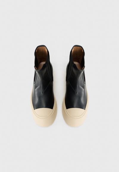 Sneakers alte in pelle nera con suola in gomma crema, caratterizzate da una texture liscia e inserti elastici sui lati per una facile calzata.