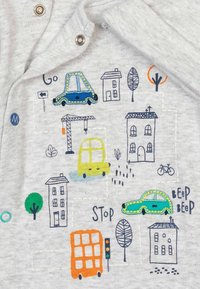 Grå stof med farverige broderede grafikker af biler, huse, træer og en kran, med teksten "Gå" og "Stop" indarbejdet i designet.