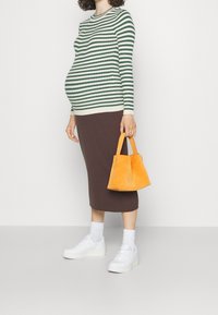 Maglione a righe verde e bianco, gonna midi marrone a coste, sneaker platform bianche e borsa a tracolla in suede arancione. 
