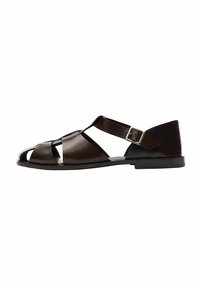 Sandali in pelle marrone con design open-toe, caratterizzati da ampie cinghie incrociate, una cinghia alla caviglia con fibbia in metallo e suola piatta.