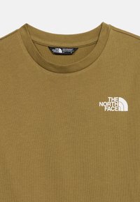 Λαδί πράσινο μπλουζάκι με στρογγυλή λαιμόκοψη και λευκό λογότυπο The North Face στο αριστερό στήθος, απλωμένο επίπεδα με ορατό γιακά και ετικέτα.