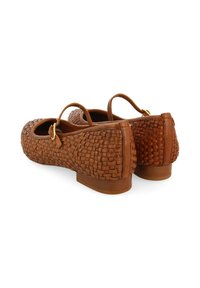 Bailarinas de cuero trenzado marrón con un tacón bajo, que cuentan con una correa con una hebilla dorada. Superficie texturizada y diseño de punta redondeada.