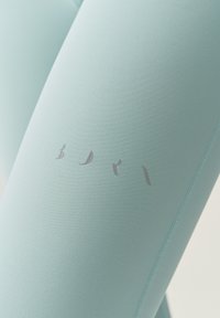 Leggings blu chiaro realizzati in un tessuto morbido e stretch, con una sottile scritta argentata e cuciture piatte per garantire comfort e durata.