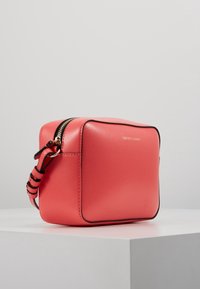 Korale skórzana torebka na ramię w kwadratowym kształcie, ze złotym zamkiem błyskawicznym i czarnymi akcentami. Posiada teksturowaną powierzchnię i regulowany pasek.