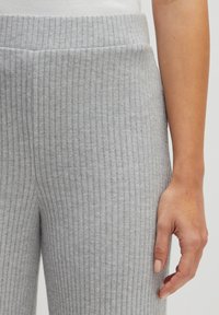 Gray ribbed pants made of soft fabric with a wide waistband. The texture features vertical stripes, blending comfort and casual design.