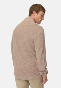 Strickpullover in einem sanften Beigeton mit strukturiertem Muster, mit einem hohen Kragen und langen Ärmeln, von hinten gezeigt.