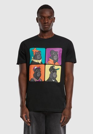Sort t-shirt med grafik af fire tegneserie-gorillaer i farverige rammer, hver iført forskellige accessoirer og outfits. Korte ærmer.