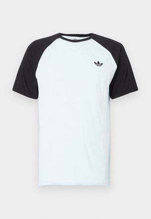 T-shirt bleu clair avec manches raglan noires, encolure ronde et petit logo noir sur la poitrine. Tissu lisse, coupe décontractée.