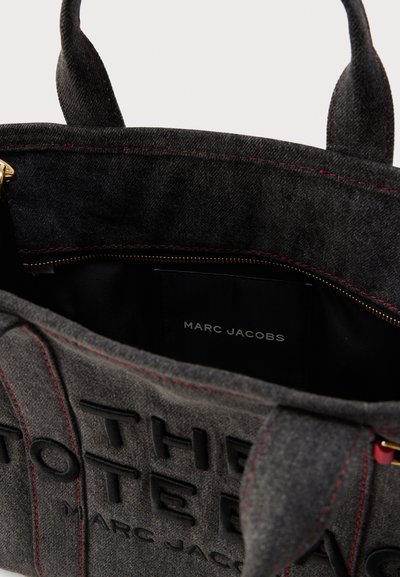 Τσάντα ώμου από μαύρο τσόχα με κόκκινη ραφή. Εσωτερική τσέπη με ετικέτα λογότυπου. Ανοιχτό πάνω μέρος με διπλές υφασμάτινες λαβές. Σχεδιασμός με δομή.