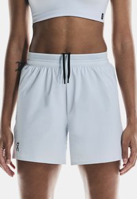 Ljusblå träningsshorts med resårmidja, justerbar svart dragsko och sidoflikar för flexibilitet. Logotyp i svart.