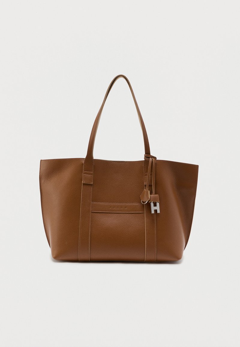 Grand sac fourre-tout en cuir marron avec deux bretelles d'épaule et un petit charm métallique en forme de "H" suspendu.