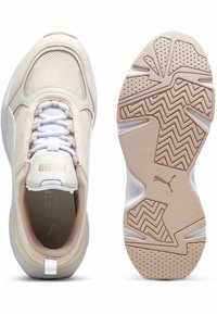 Baskets légères avec une tige en mesh de couleur crème et marron clair, dotées de lacets blancs et d'une semelle en caoutchouc texturée avec un motif en zigzag.